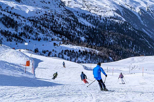 Een uitzicht op de besneeuwde Alpen met skiërs die skiën op een skipiste